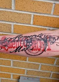 手臂彩色骷髅与夸张的花体字母纹身图案