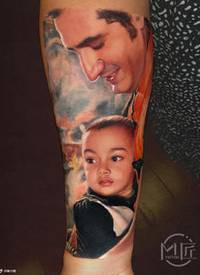 宝宝肖像写实纹身一位来自印度的妈妈，把老公抱着儿子的照片纹在了手臂上，父亲看着孩子的眼神满是宠溺。对于深色皮肤纹彩色纹身，还是有一定难度的。在用色方面尽量选取冷一点的颜色来做背景，这样能更好的突出人物